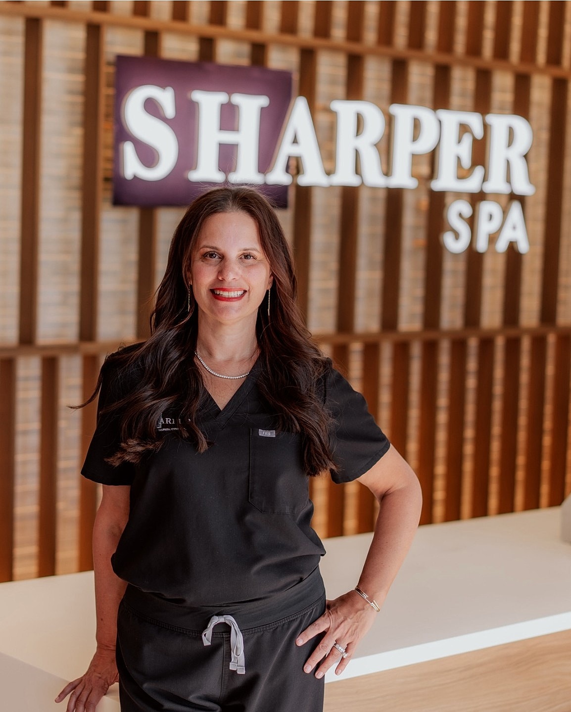 Spa professional posing with Sharper Spa sign.