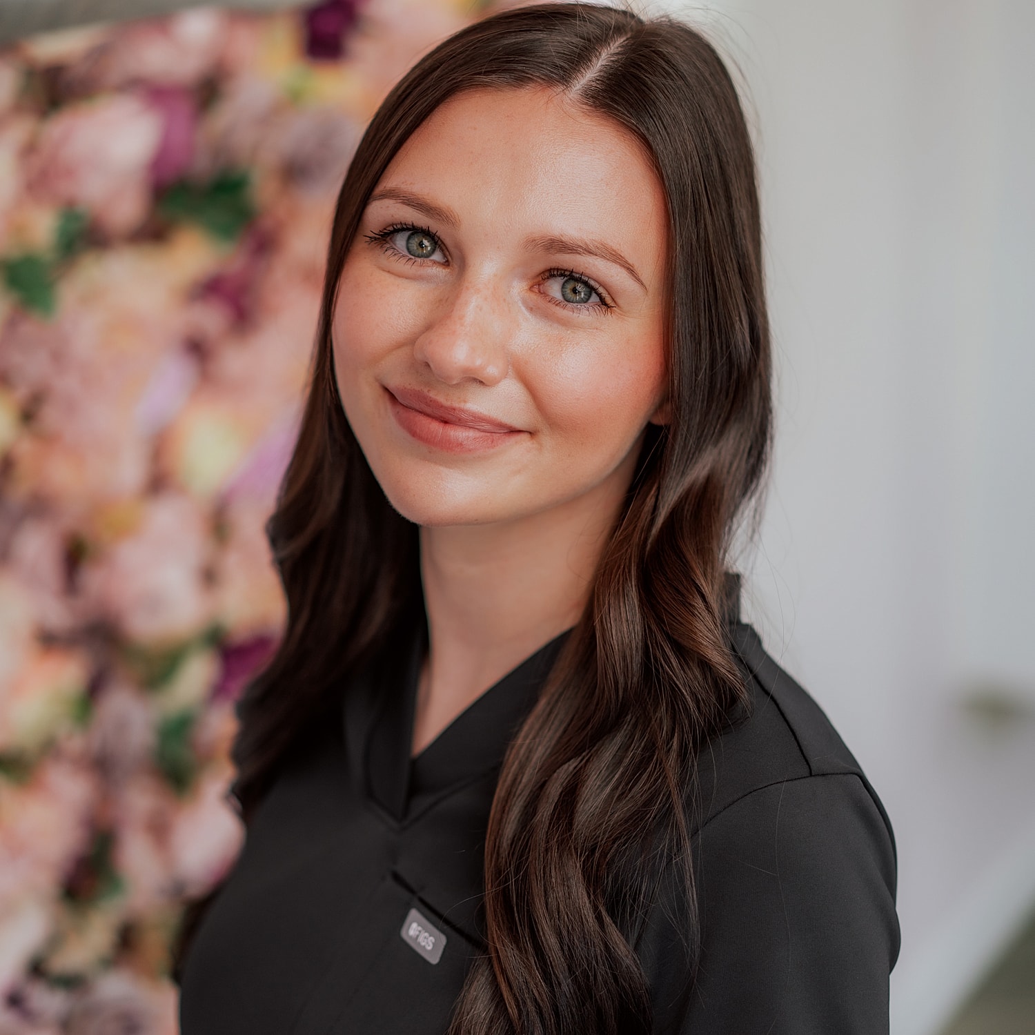 Smiling woman in professional attire with floral background
