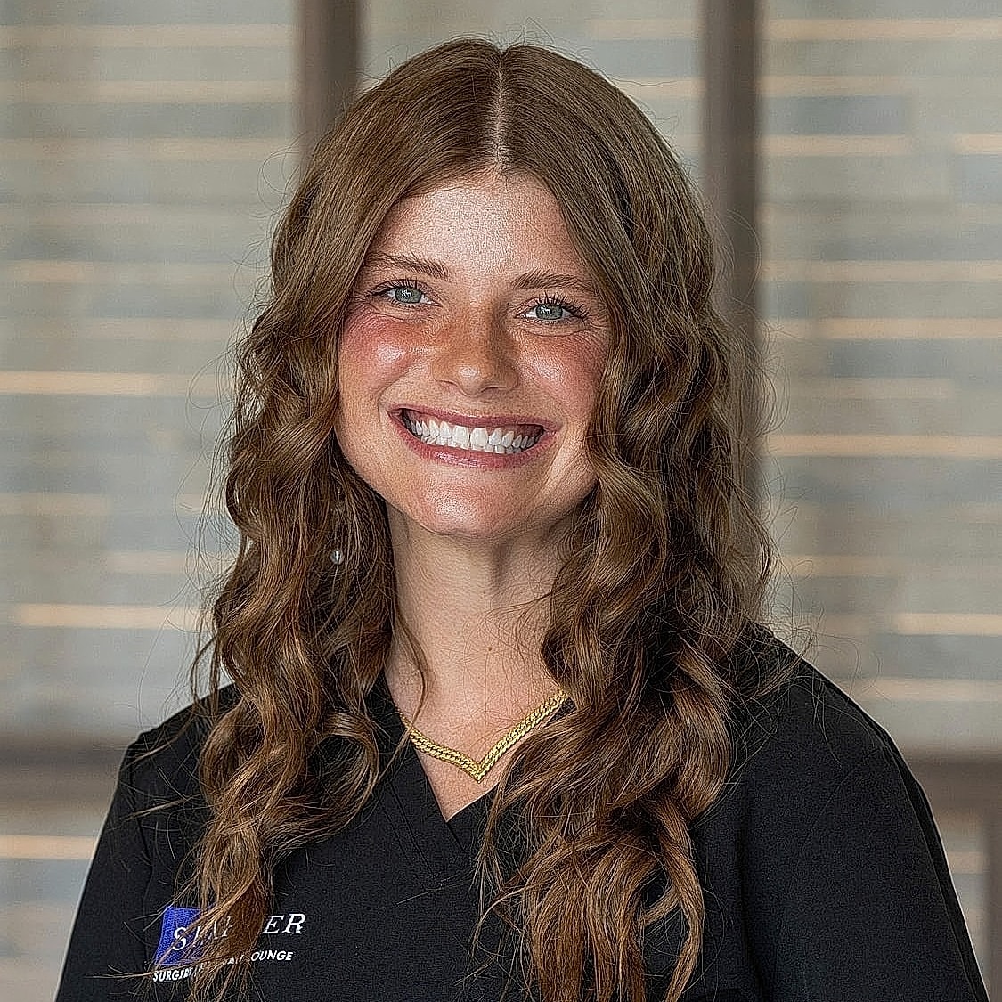 Smiling professional with curly hair in uniform.