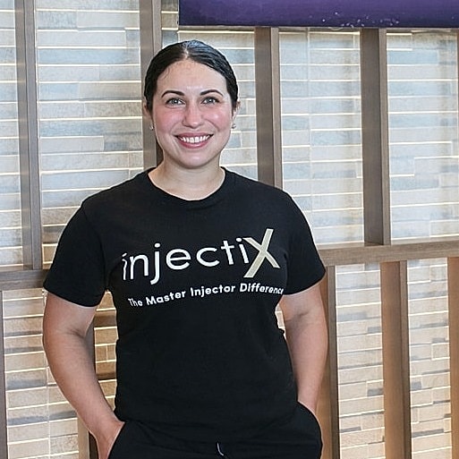 Spa employee posing beside Sharper Spa sign.