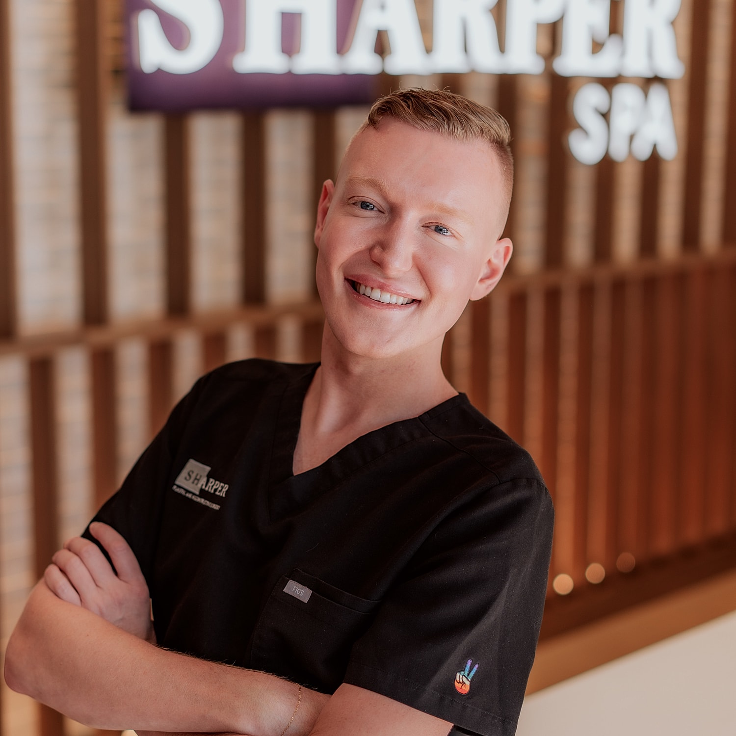 Smiling spa professional in black uniform.