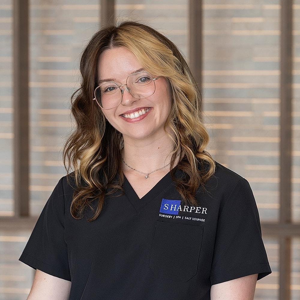 Smiling woman in professional attire, medical setting.