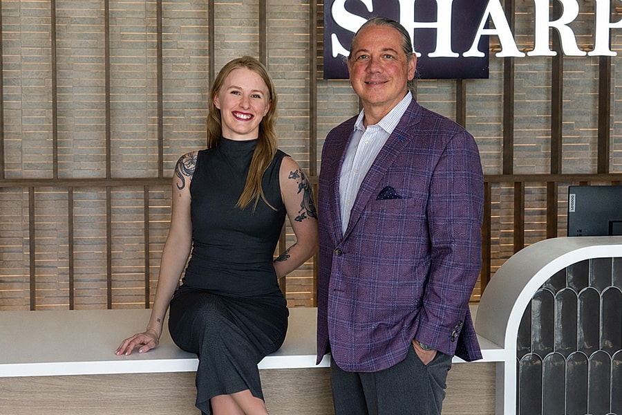Two professionals posing at a reception desk.