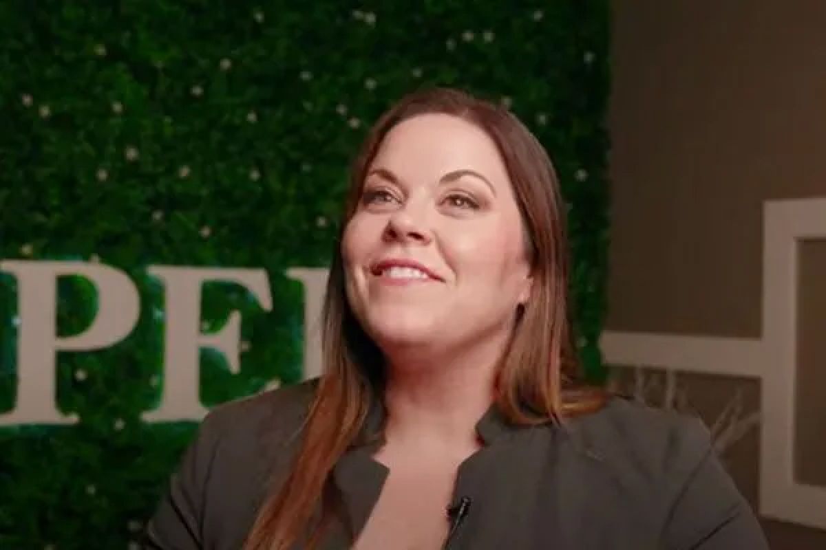 Woman smiling against a green background.