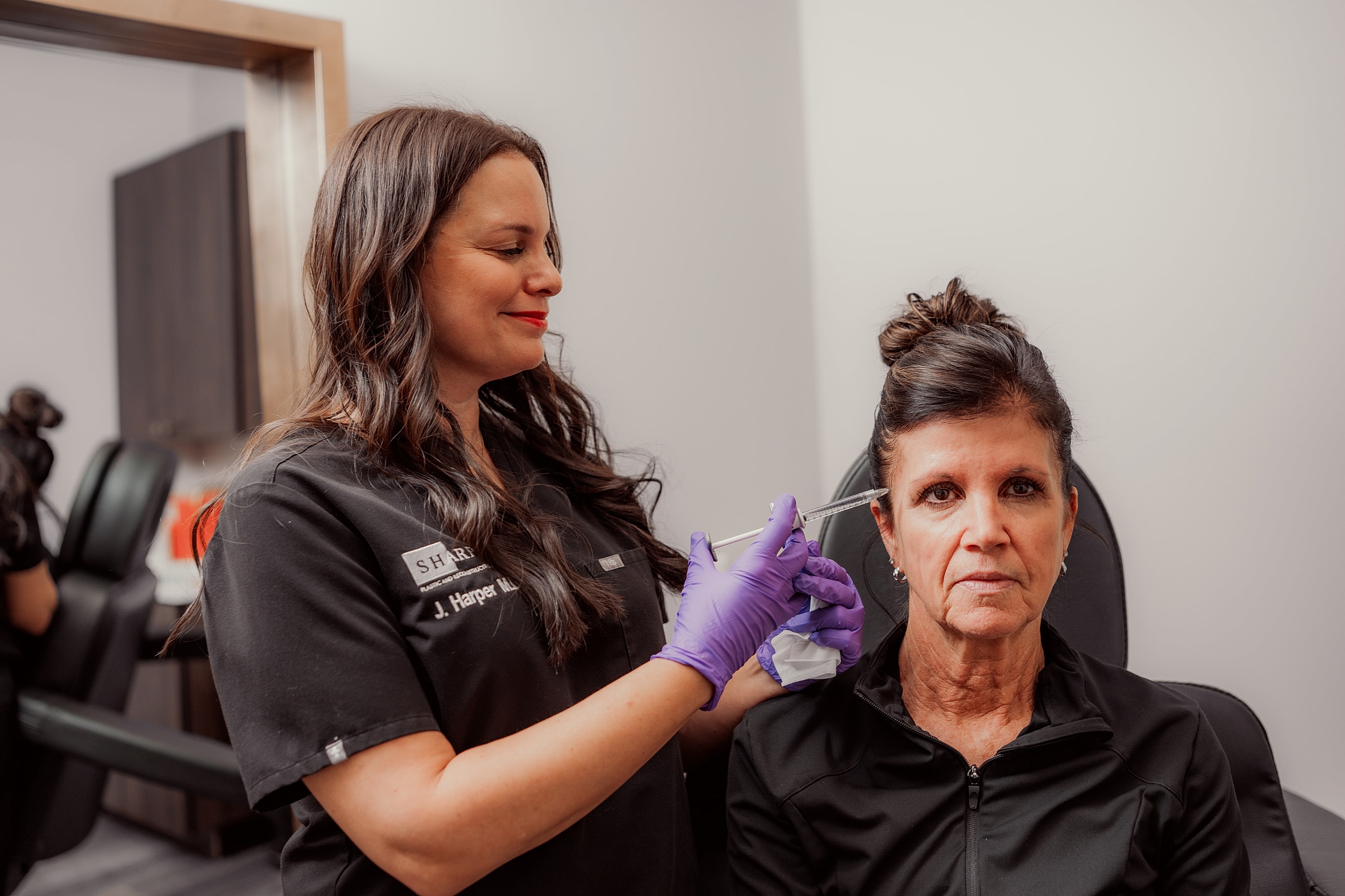 Woman examining reflection in mirror at clinic.