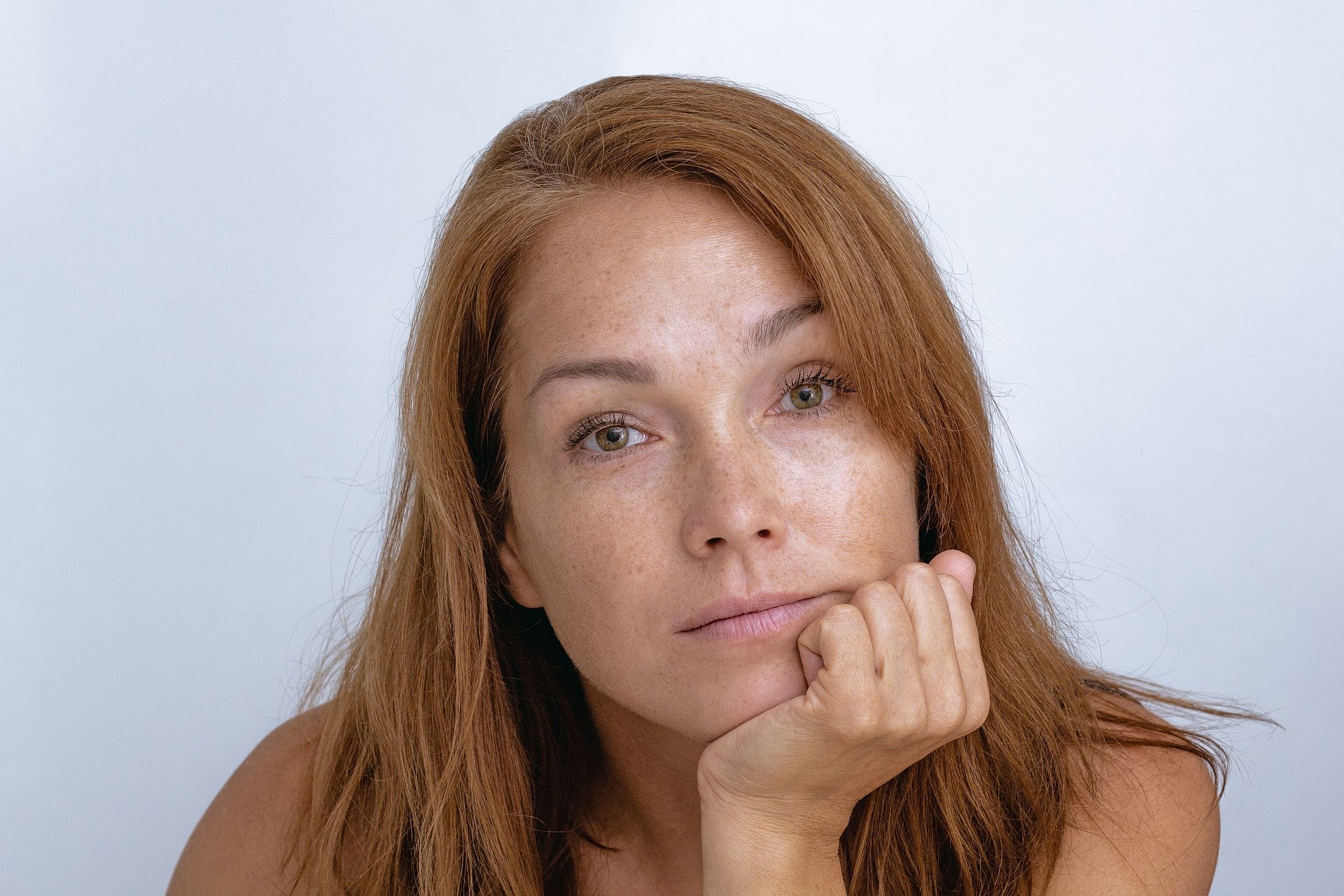 Thoughtful woman resting chin on hand.